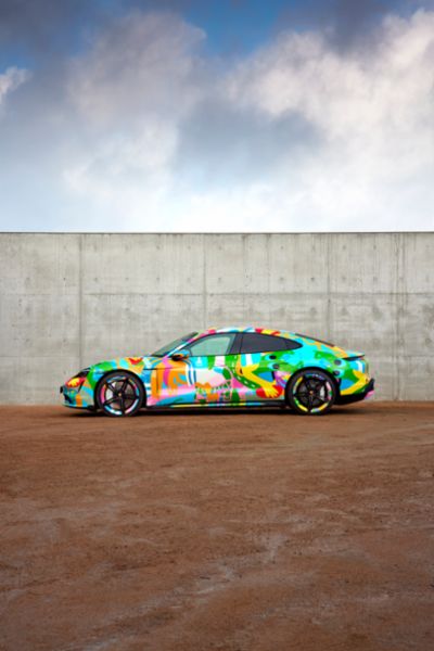 Porsche Taycan in front of a blue sky and stone wall 