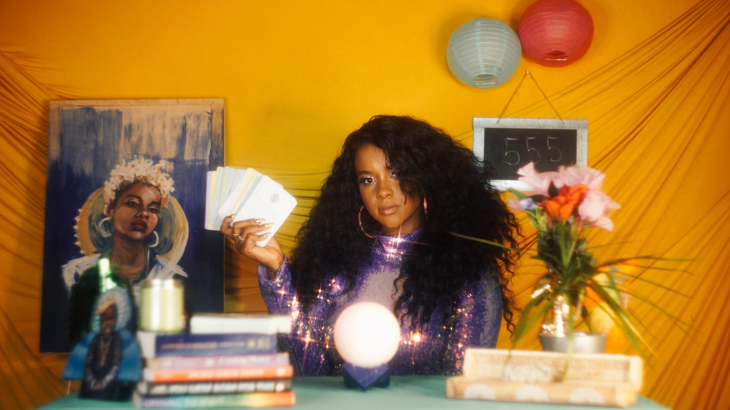 NFT Artist Latasha holding up a set of cards from behind a table